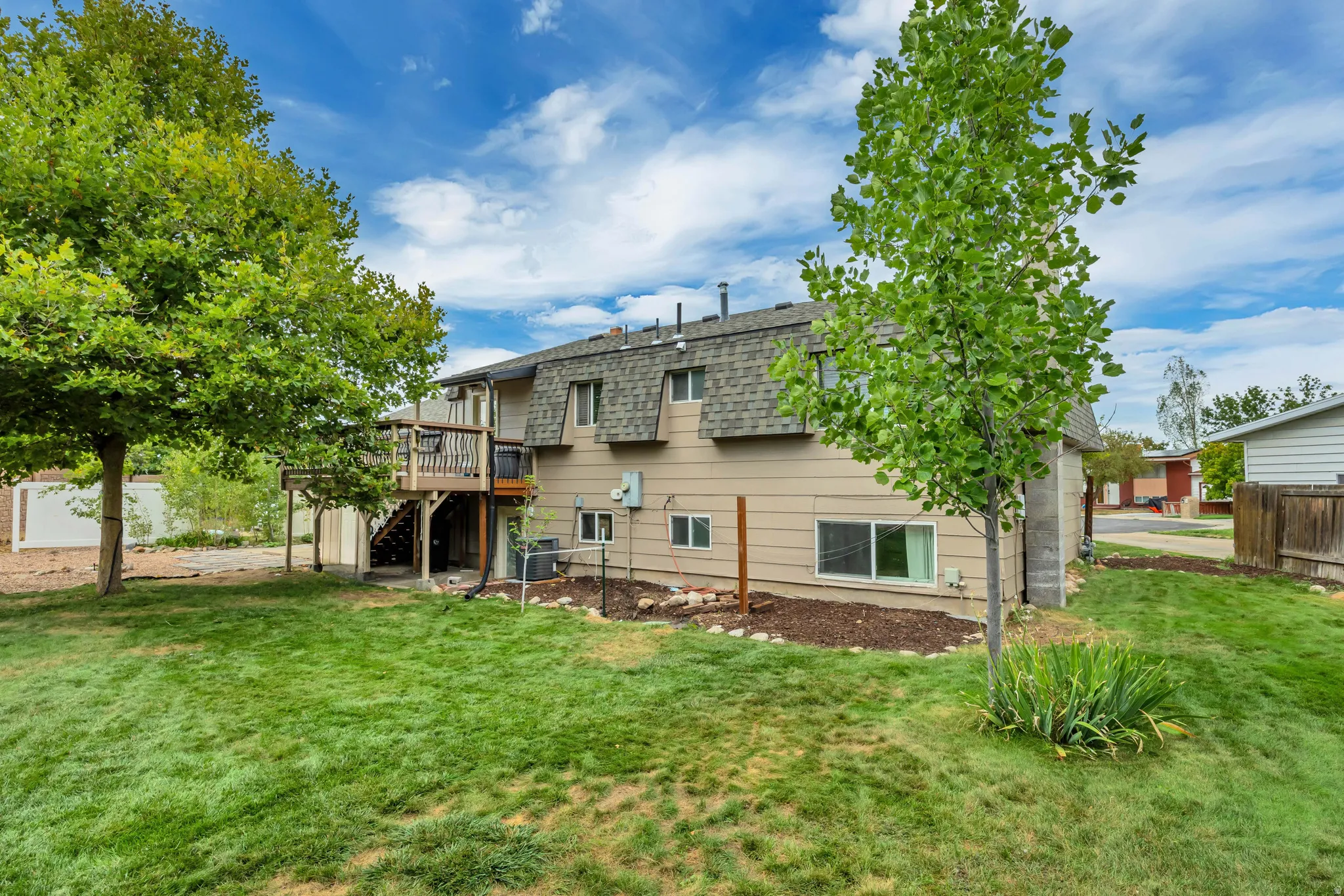 Expansive backyard with lawn, established trees, and a multi-level wood deck