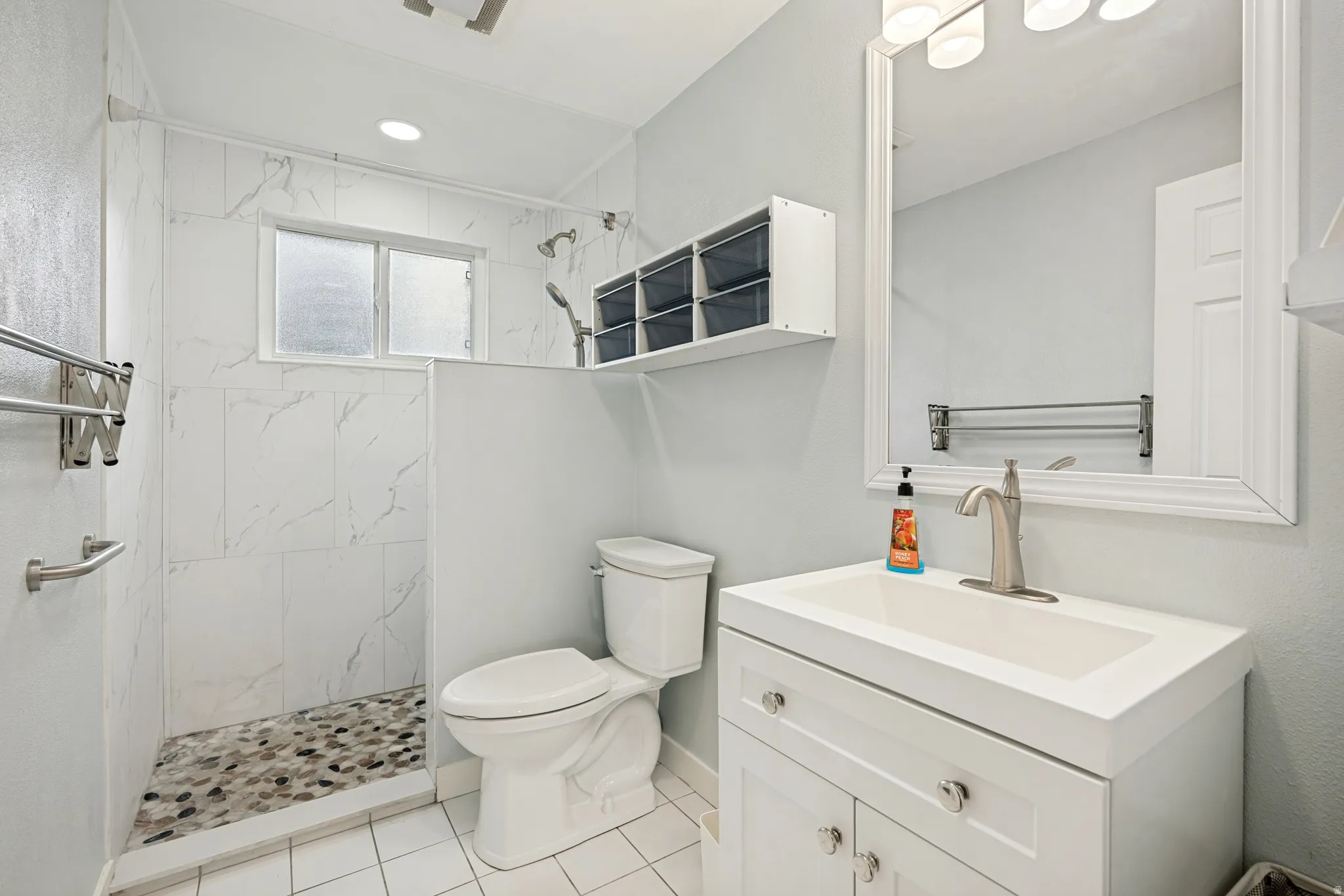 Walk-in shower with pebble tile flooring and white tiled walls