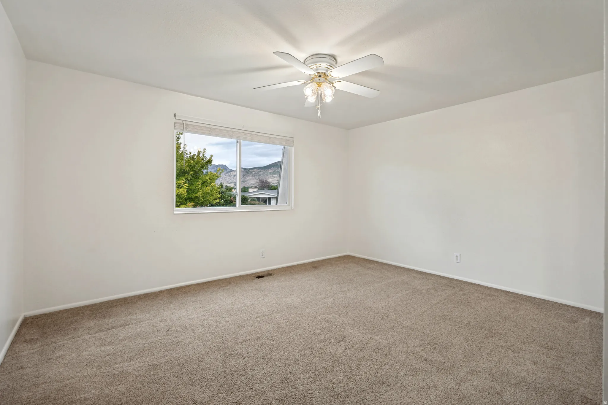 Neutral-toned carpeting, white walls, and a ceiling fan with integrated lighting