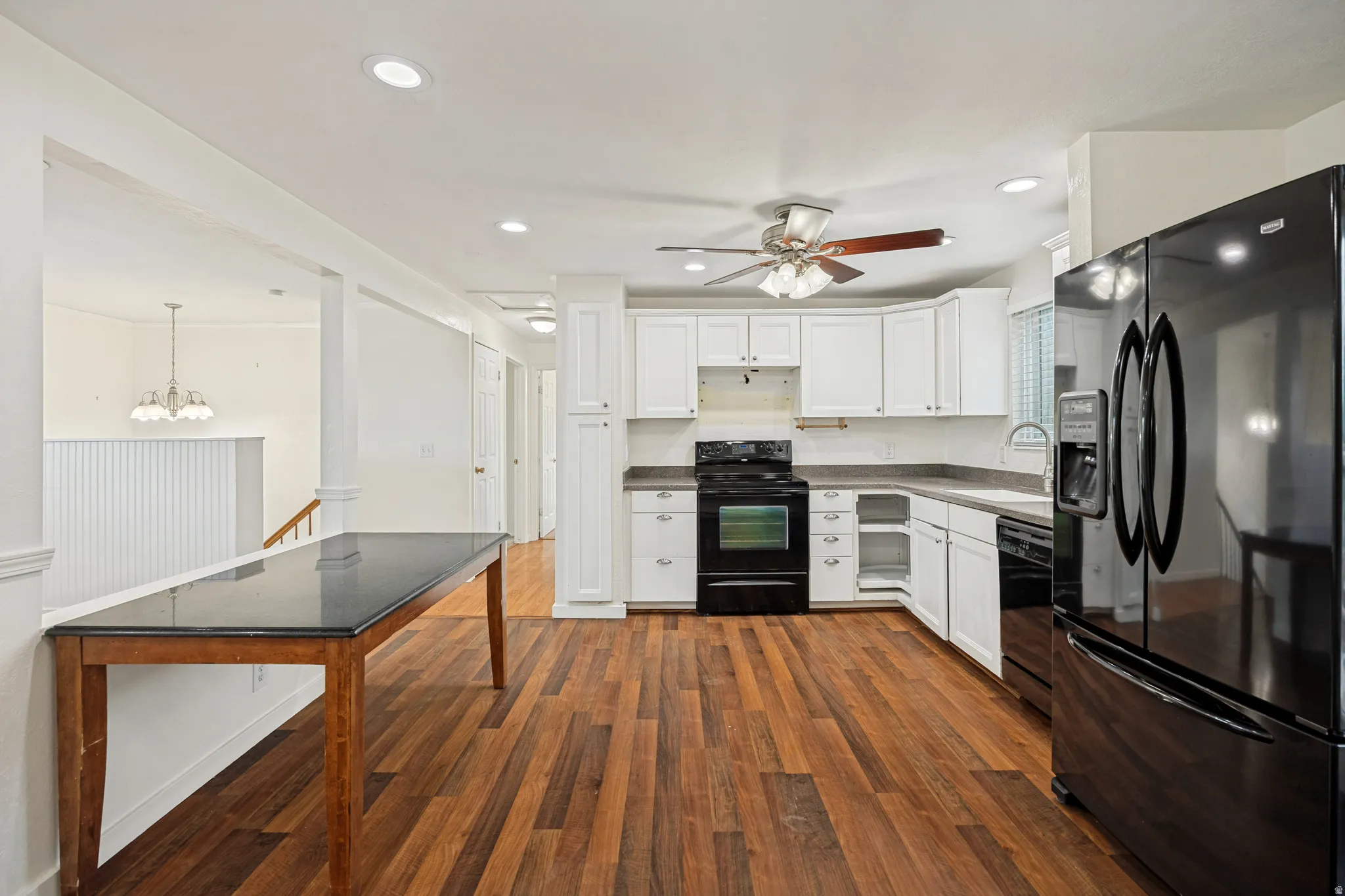 Kitchen with wood-finish flooring, white cabinetry, dark countertops, and recessed lighting