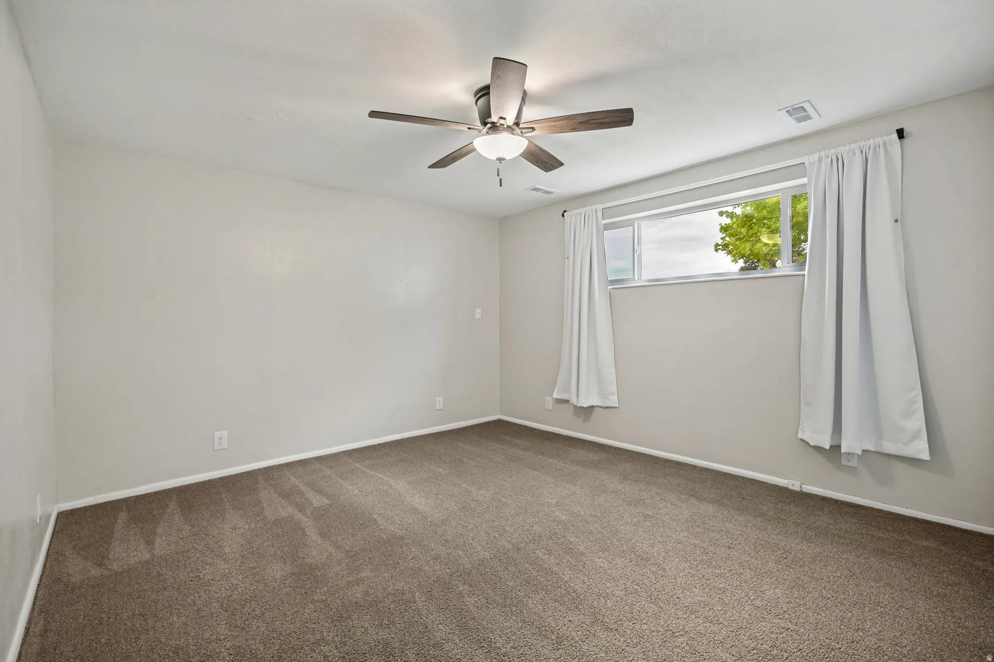 Recessed window with white trim, ceiling fan with integrated lighting, and neutral carpeting