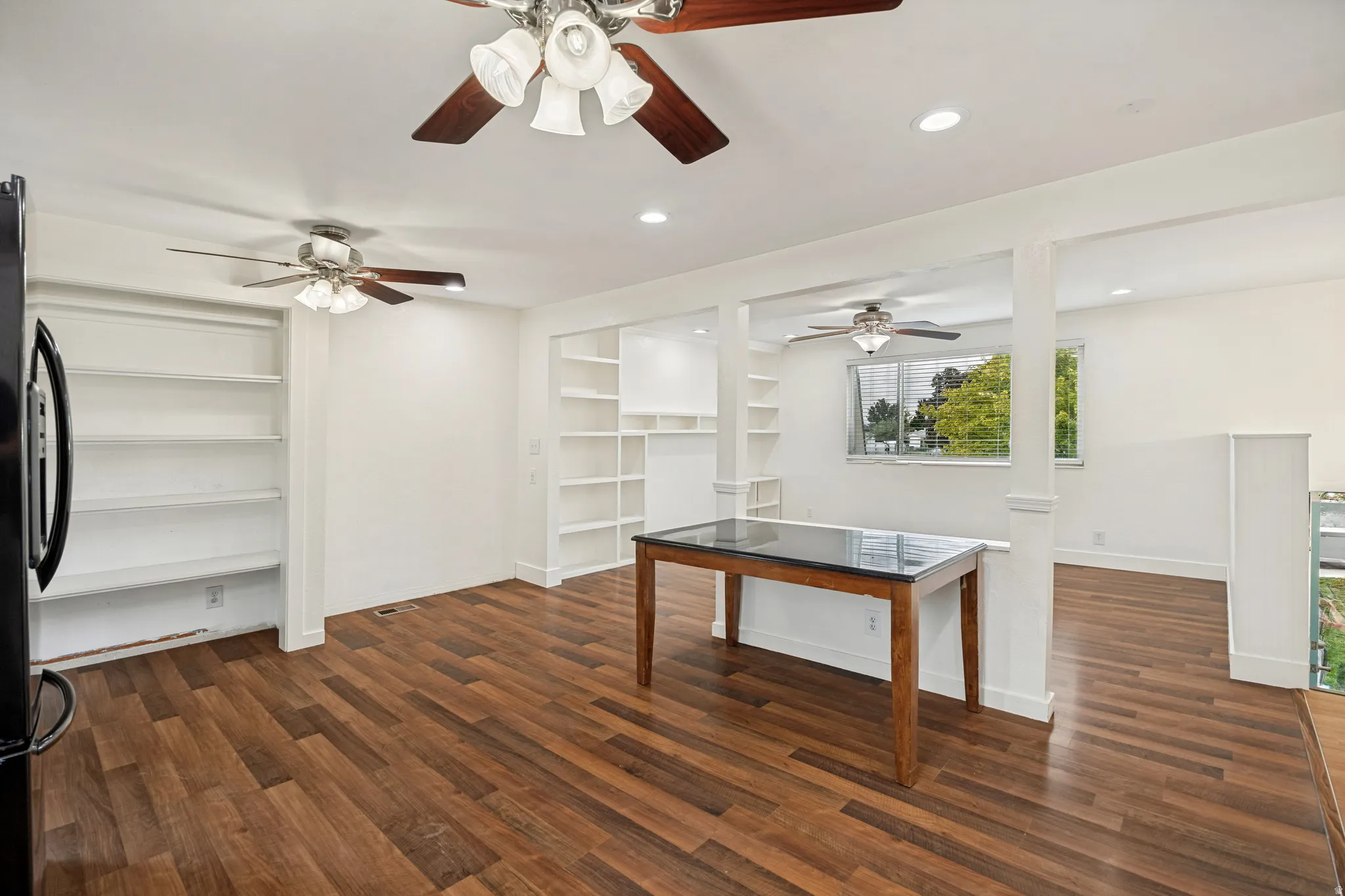 Gathering and dining area. Wood-finish flooring, recessed lighting, and built-in shelving units