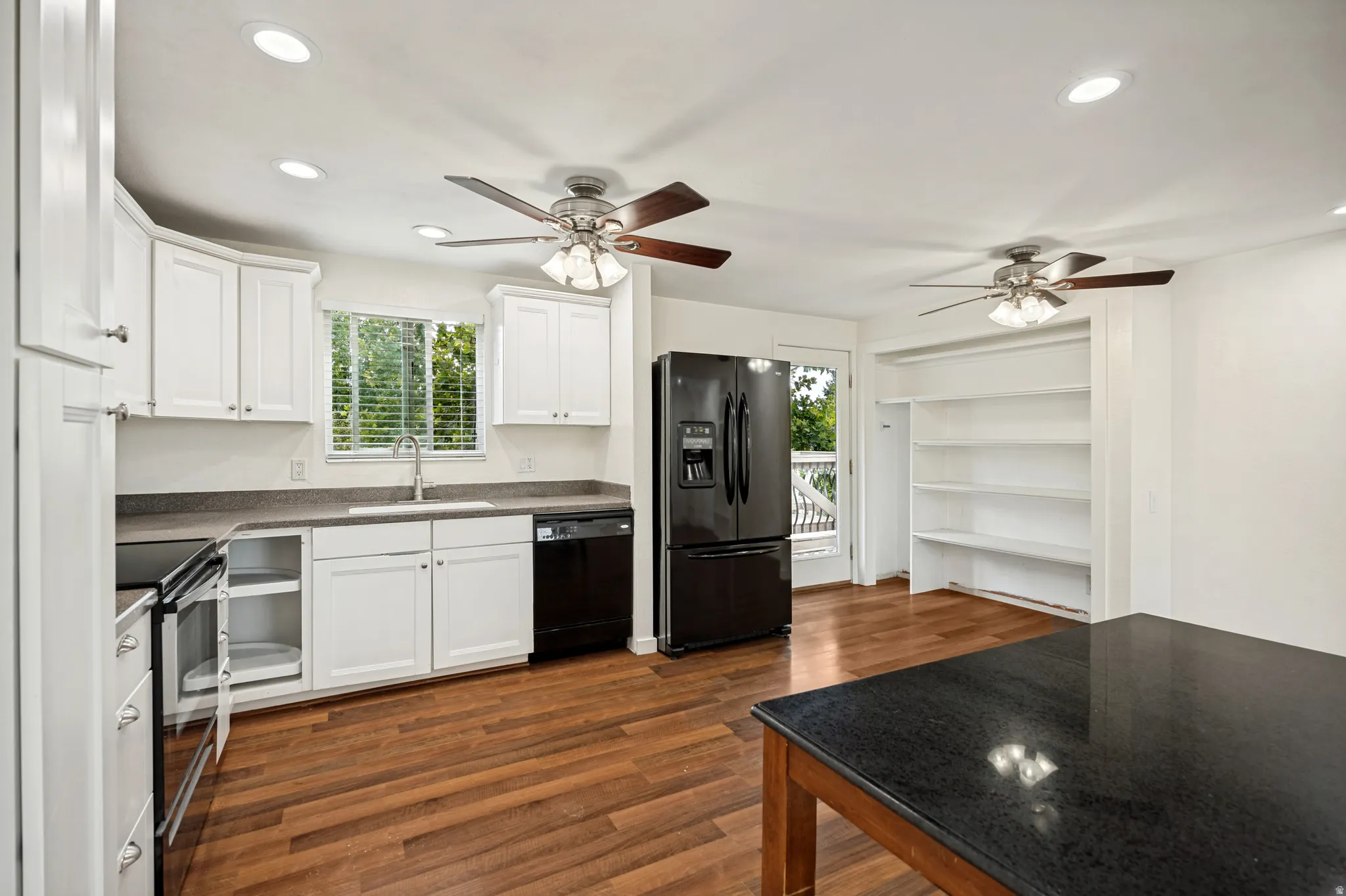 Kitchen featuring white cabinetry, dark countertops, wood-finish flooring, recessed lighting, and built-in shelving