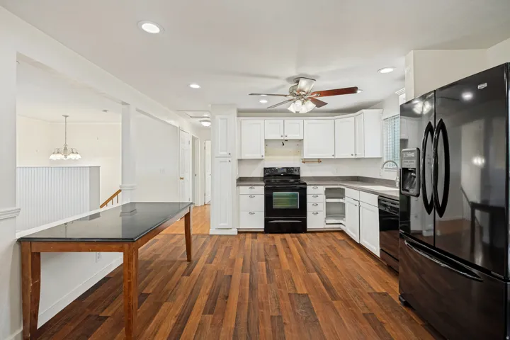 Kitchen with wood-finish flooring, white cabinetry, dark countertops, and recessed lighting