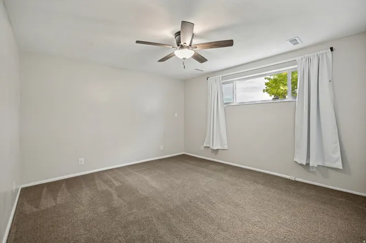 Recessed window with white trim, ceiling fan with integrated lighting, and neutral carpeting