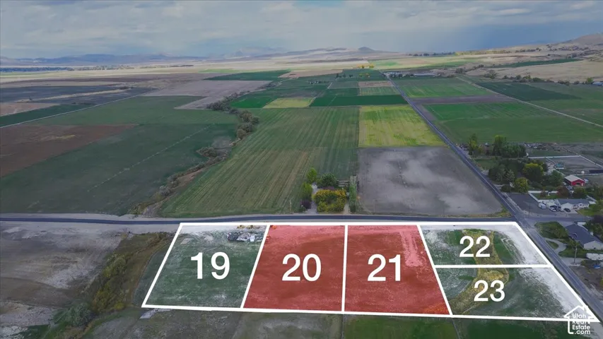 Aerial perspective of expansive rural acreage featuring vast open land, natural terrain, and prominent mountain backdrops