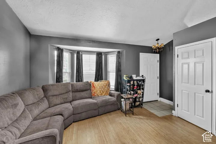 Bay window with blinds, wood-finish flooring, paneled interior doors, ceiling-mounted light fixture, and tiled entry