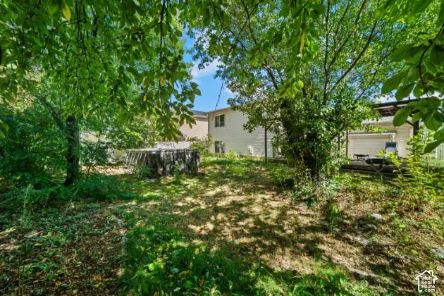 Expansive backyard with mature trees, established plantings, and a raised wooden deck