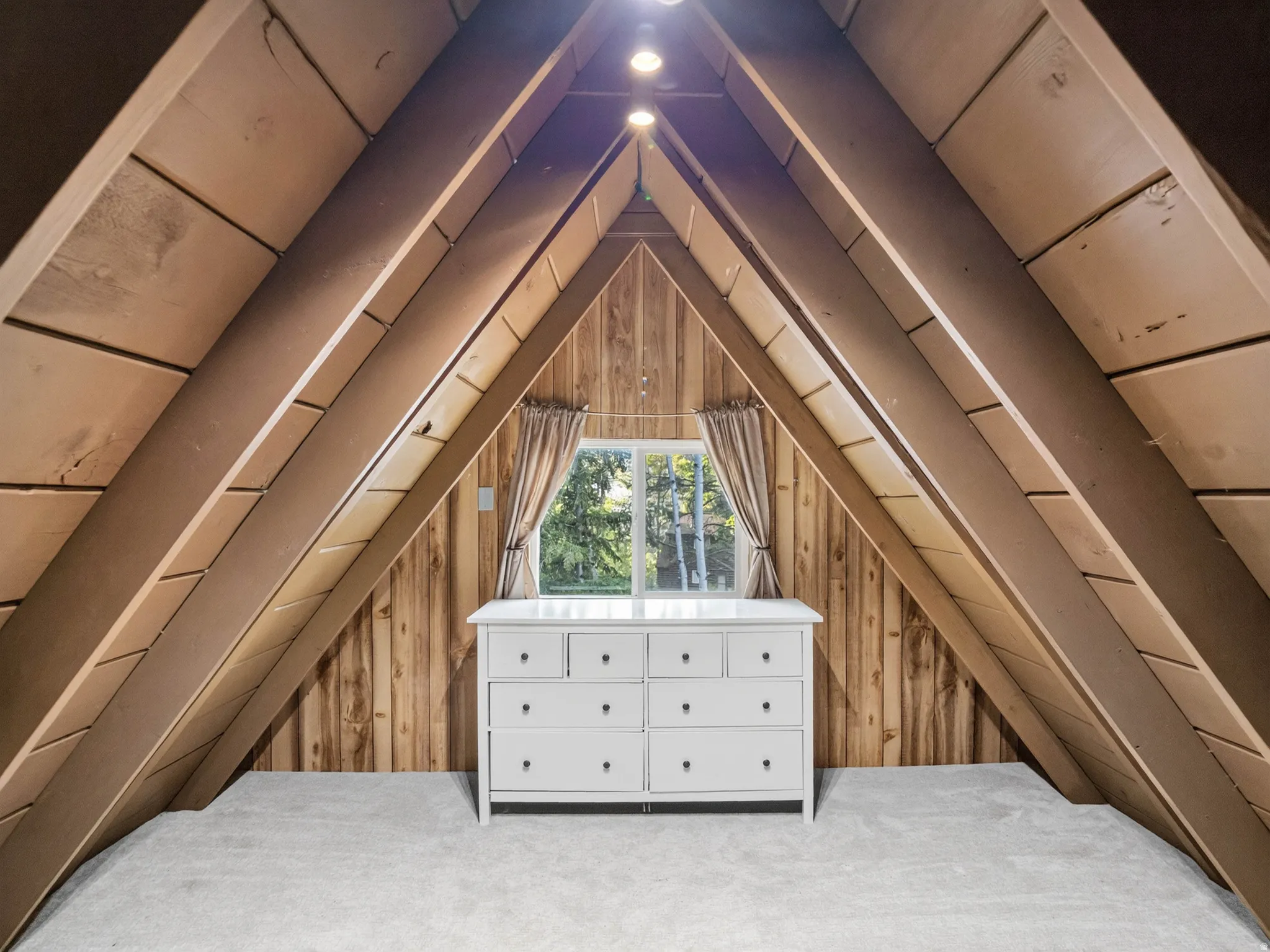 Vaulted ceiling with exposed wood beams, wood-paneled walls, and soft carpeting