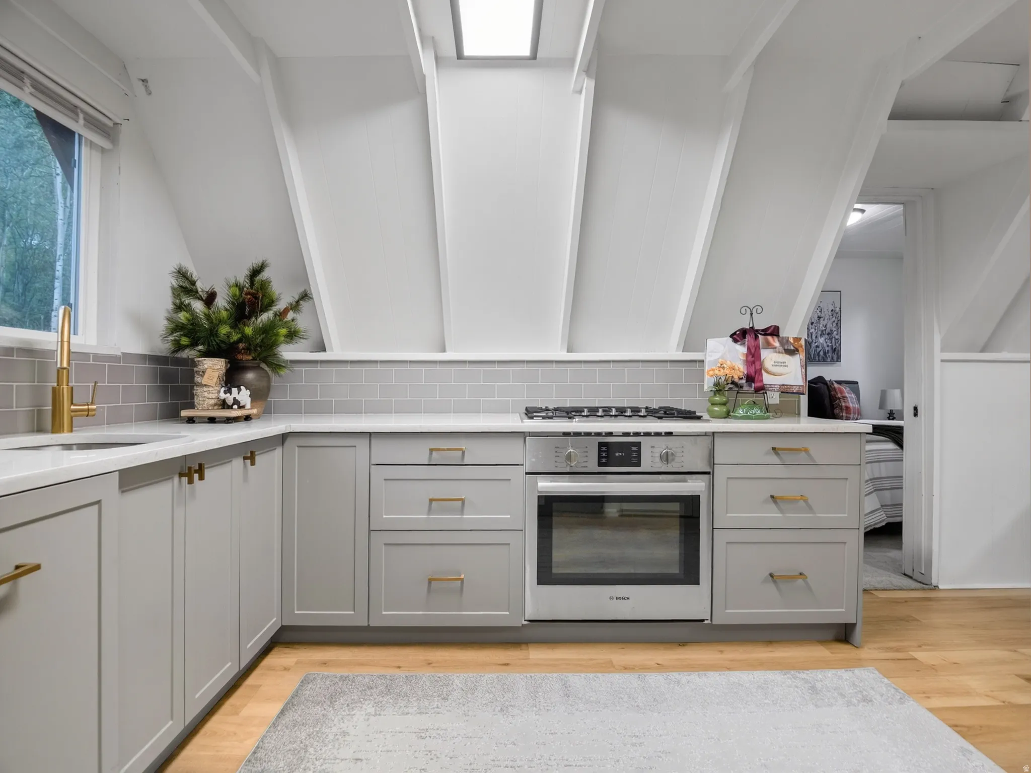 Contemporary kitchen featuring light gray cabinetry, quartz-finish countertops, subway tile backsplash, and a built-in oven with a gas cooktop