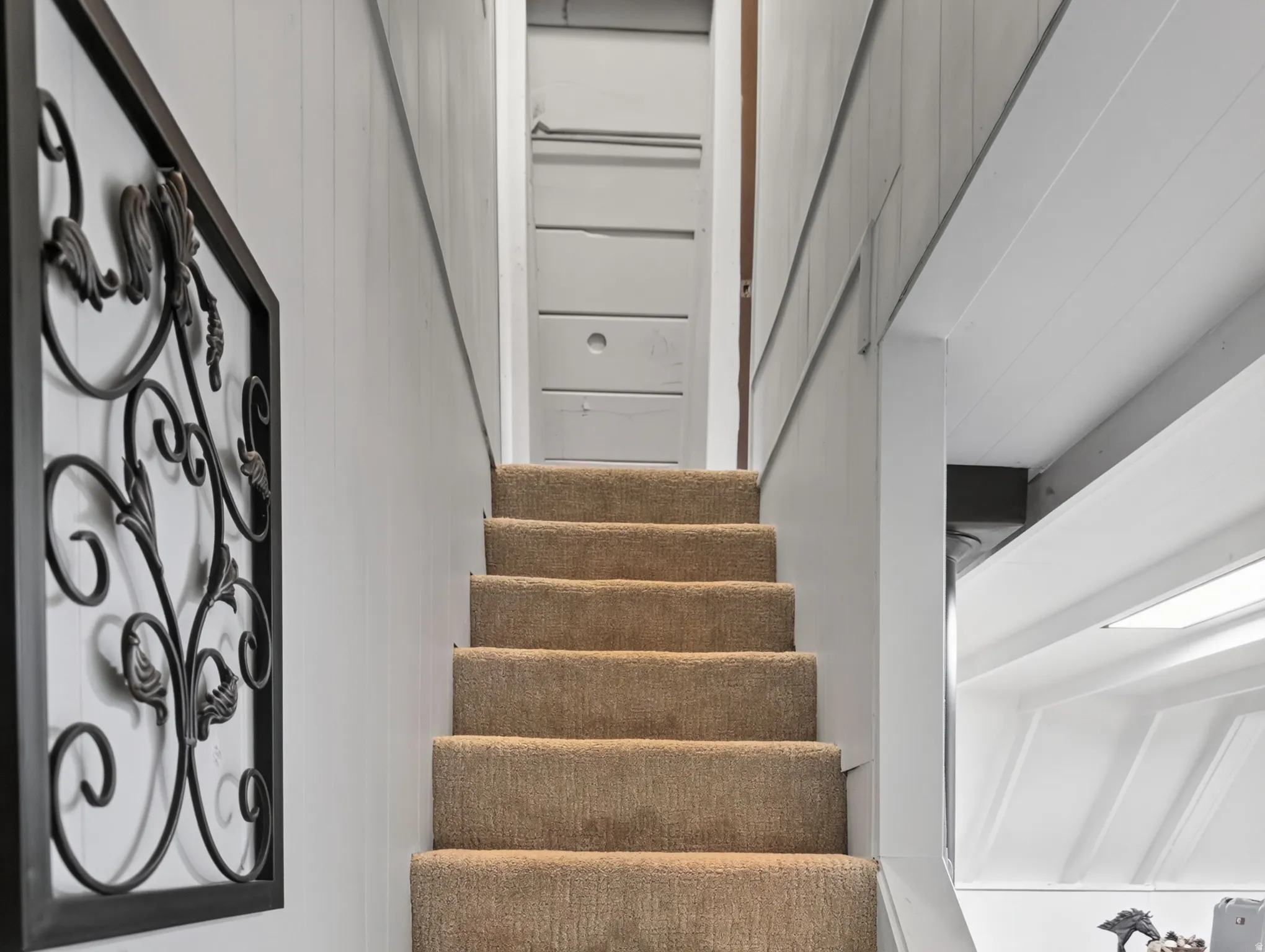 Carpeted staircase with paneled walls
