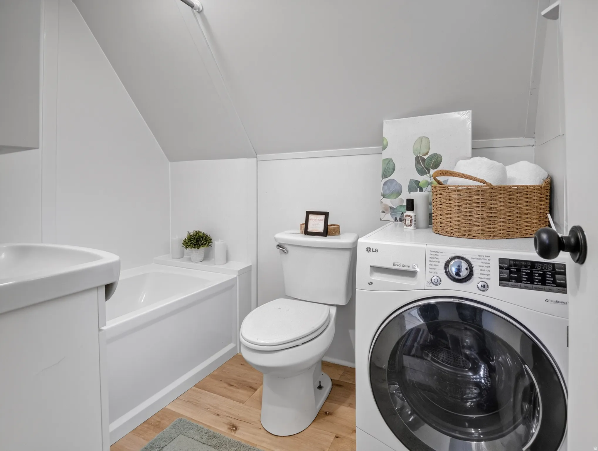 White bathroom featuring a built-in tub, toilet, and wood-finish flooring