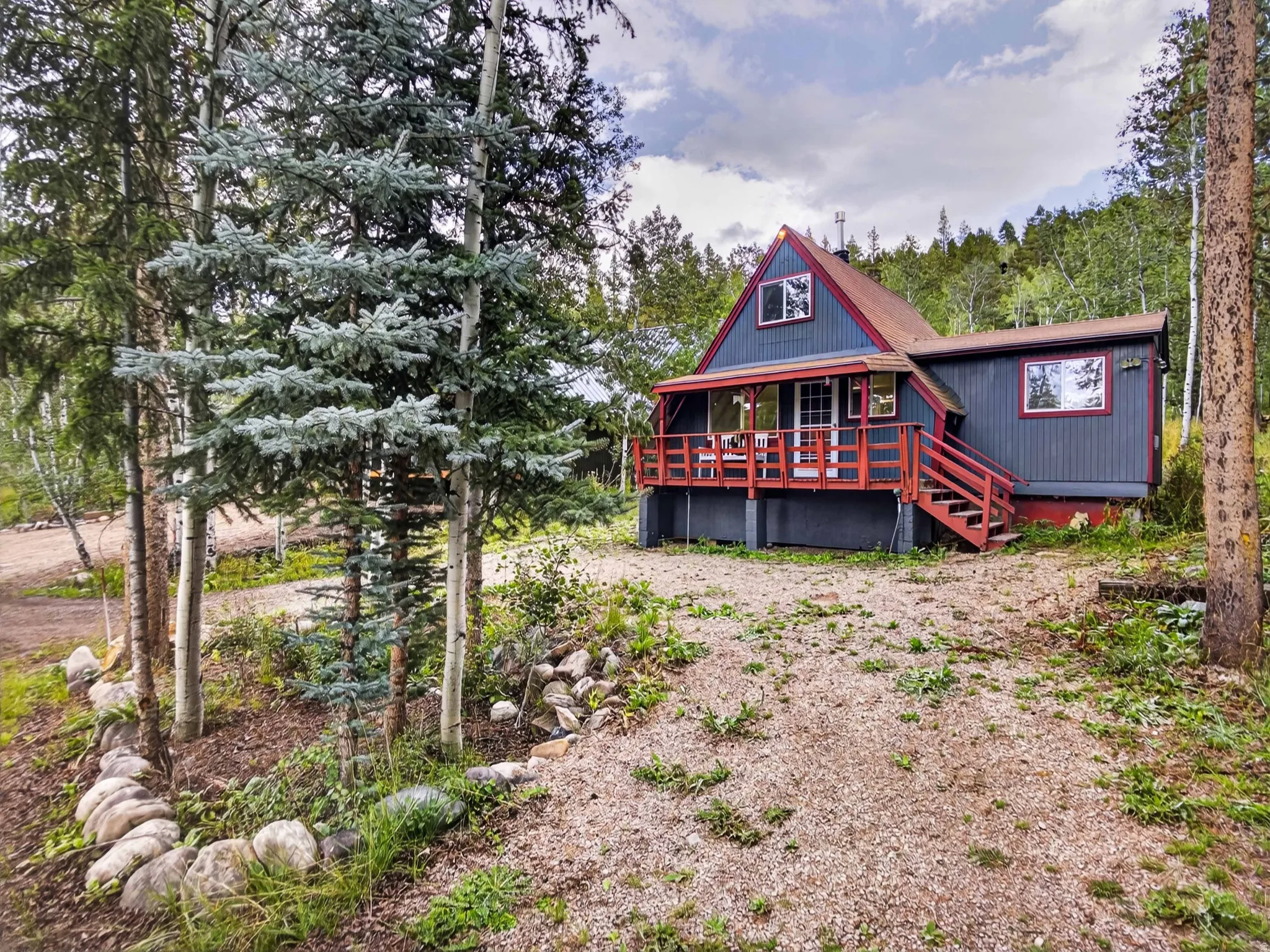 A-frame style residence featuring a covered deck with red railings, a red roof, and a gray exterior