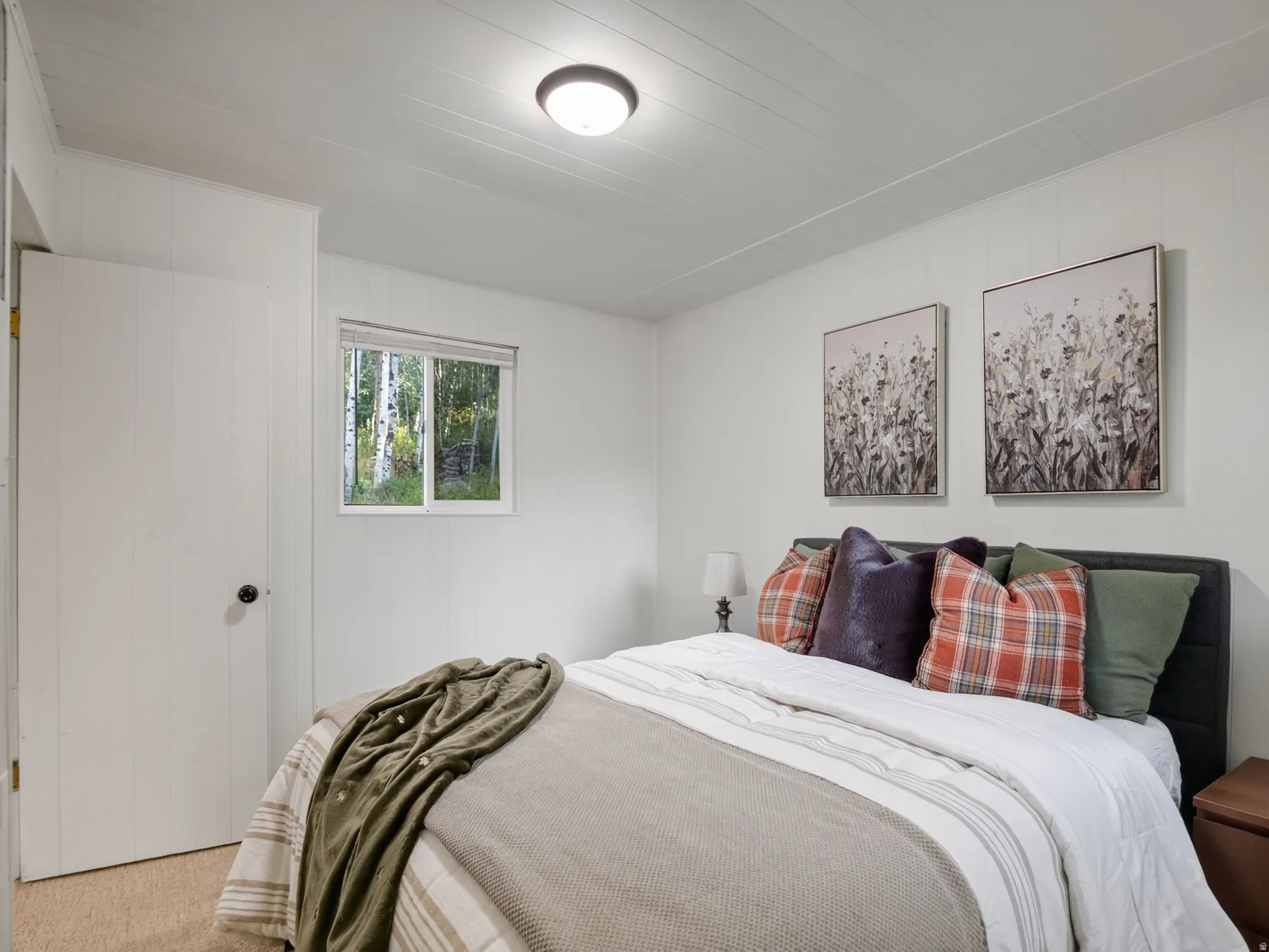 White paneled walls, recessed window, white ceiling with flush-mount lighting, and carpeted flooring