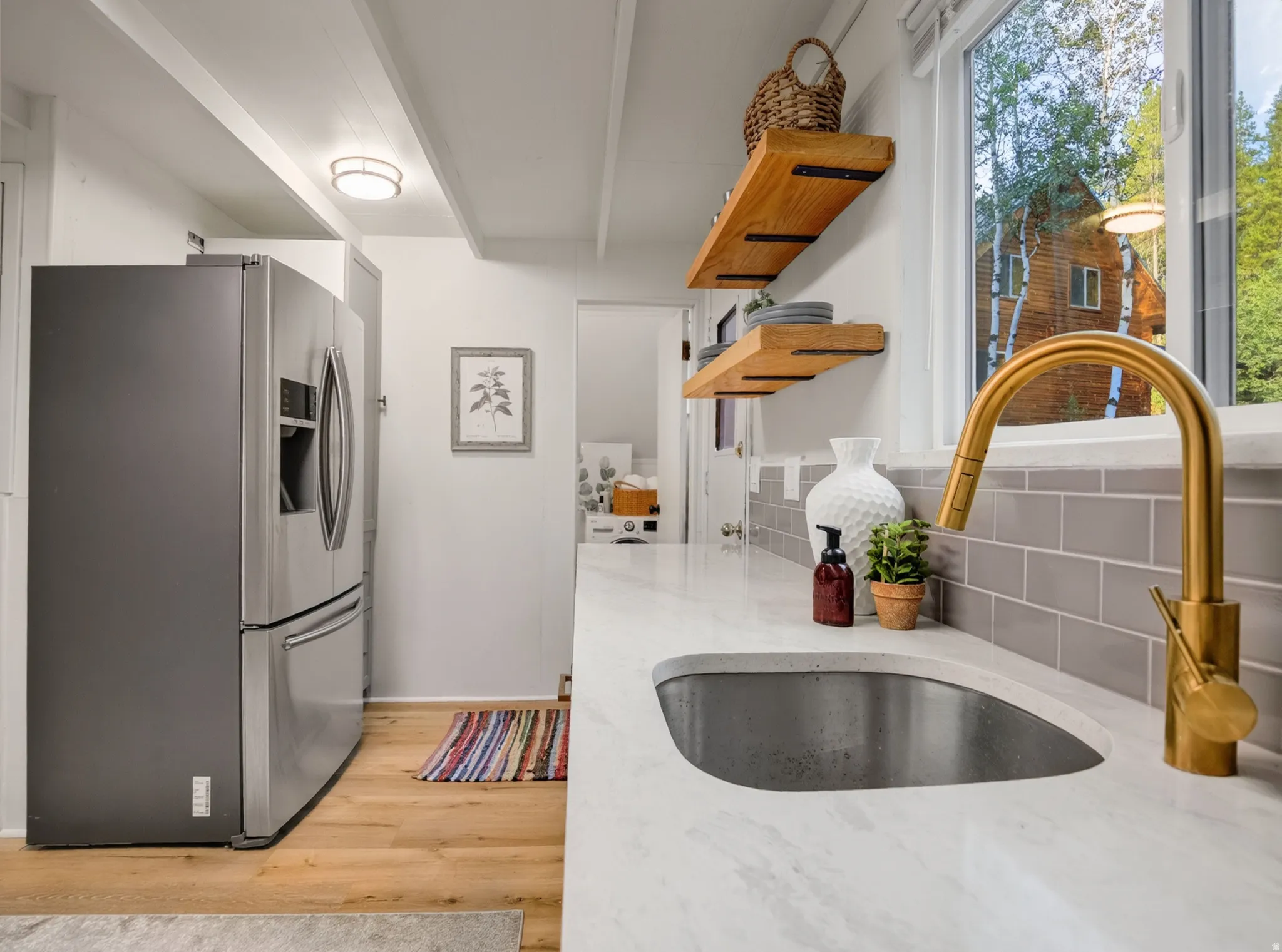 Built-in sink with gold-finish faucet, subway tile backsplash, and light wood-finish flooring