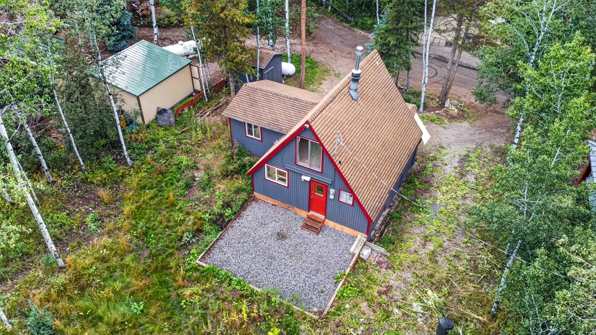 A-frame residence with a red entry door and a gravel patio