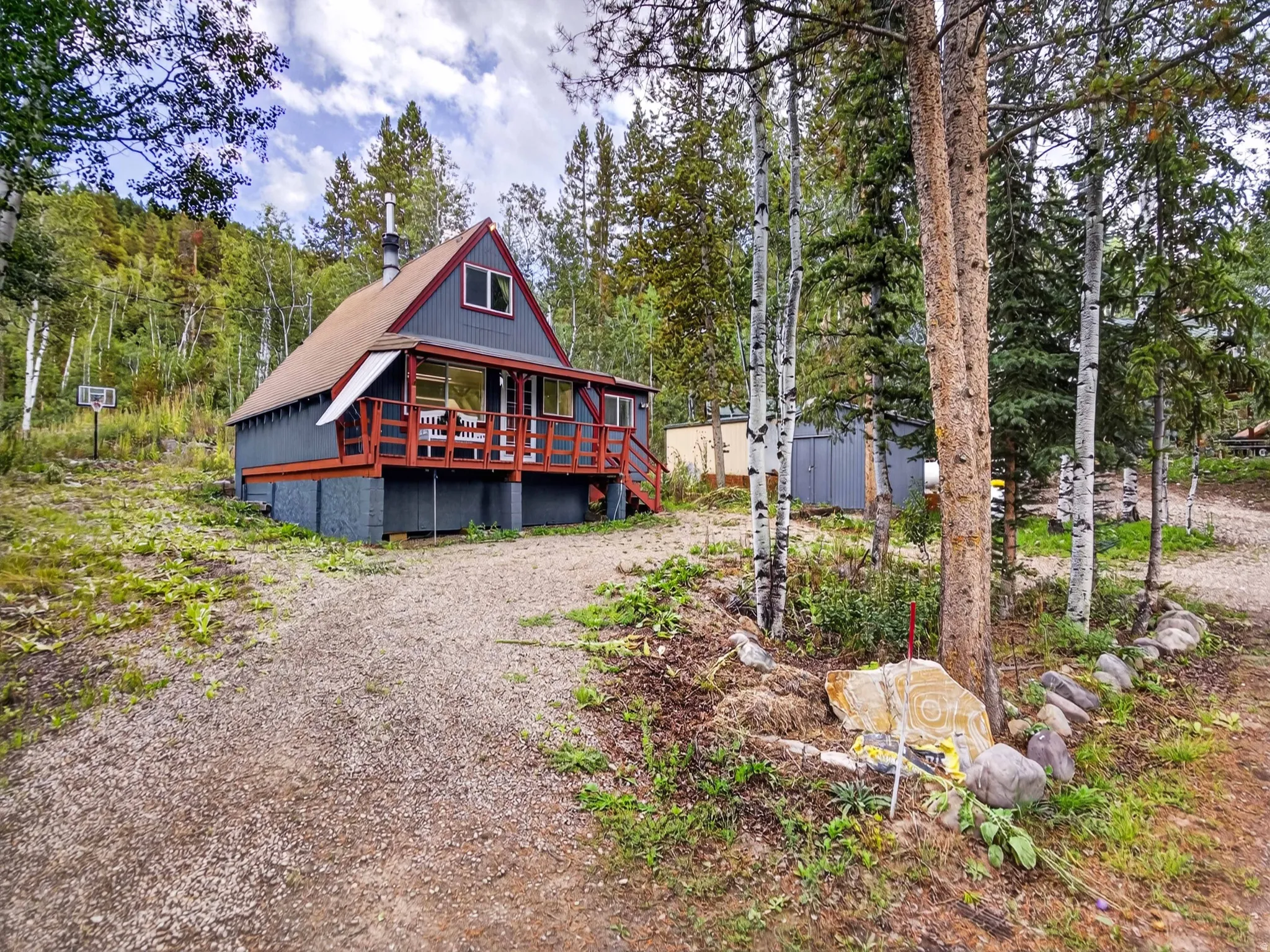 A-frame residence with an expansive front deck, surrounded by mature trees