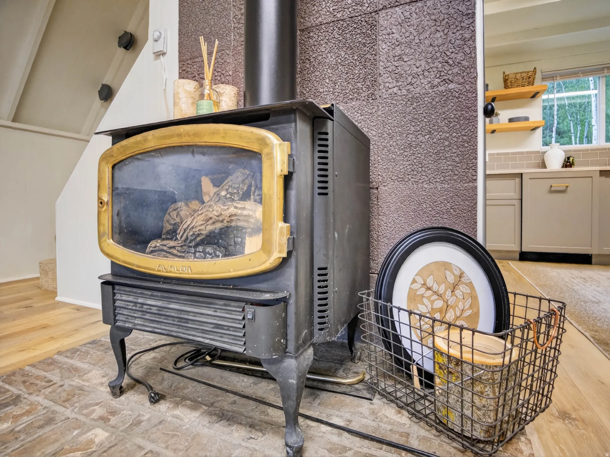 Black wood-burning stove with a brass-finish door on a brick-style hearth