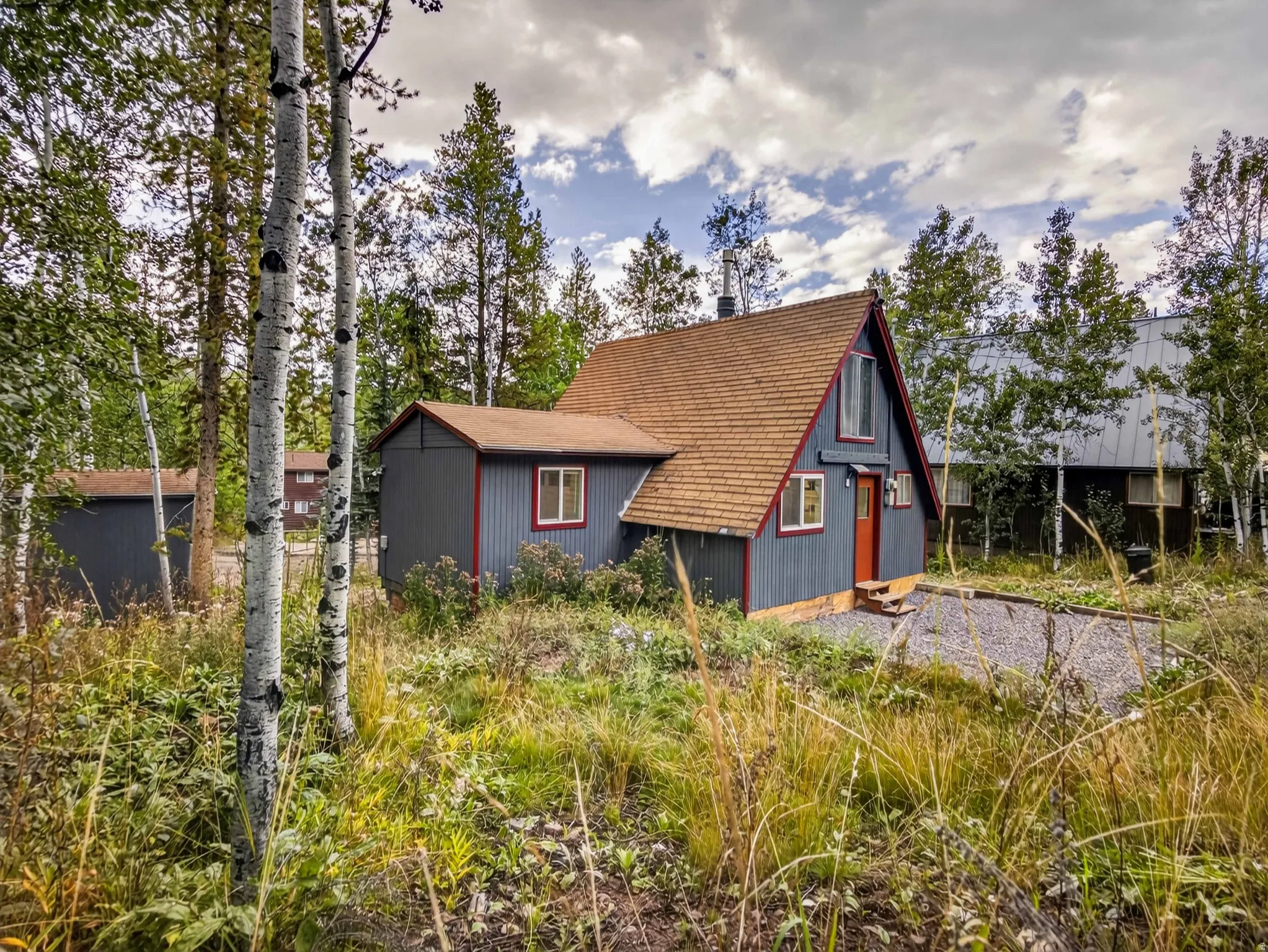 A-frame style residence with a warm-toned shingle roof, dark gray siding, and contrasting red trim