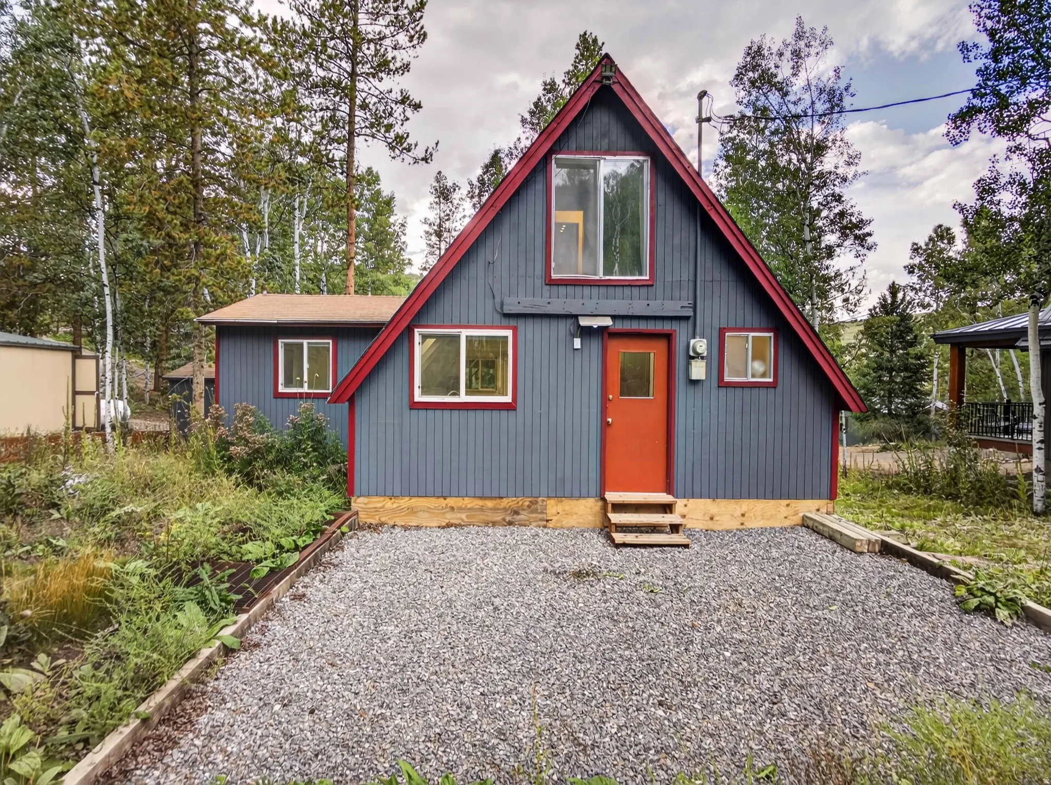 A-frame style exterior with vertical siding, contrasting trim, and a vibrant entry door