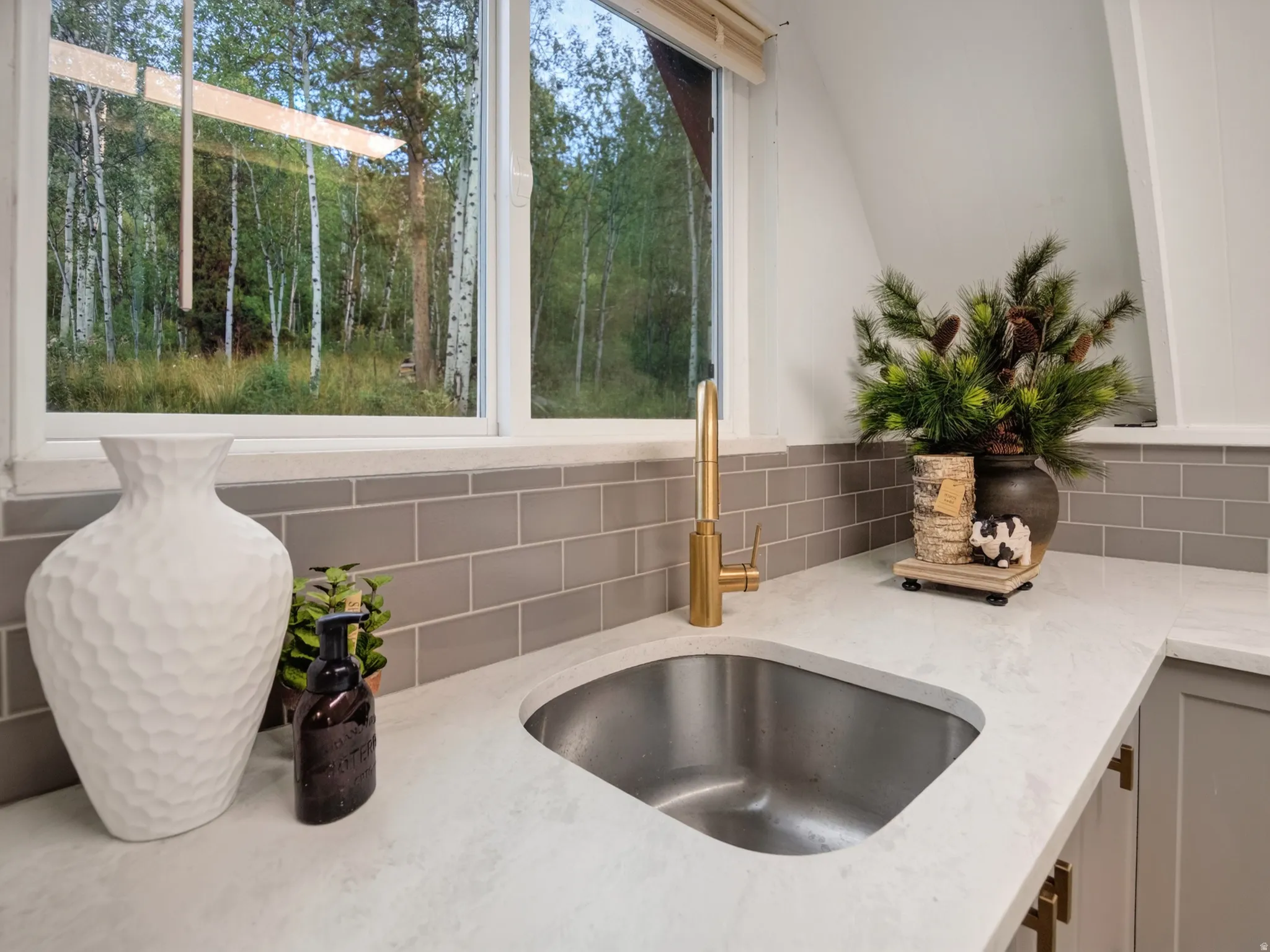 Stainless steel undermount sink with a brass-finish gooseneck faucet, set within a light-colored countertop