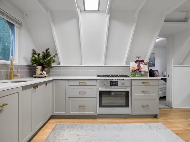 Contemporary kitchen featuring light gray cabinetry, quartz-finish countertops, subway tile backsplash, and a built-in oven with a gas cooktop