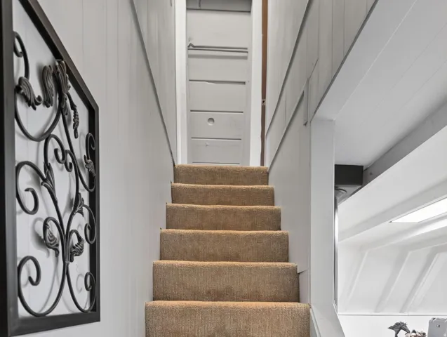 Carpeted staircase with paneled walls