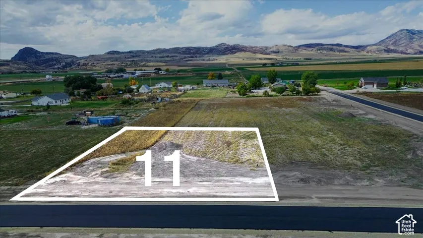 Expansive rectangular parcel of land featuring direct paved road access and mountain range backdrops