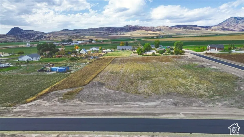 Vacant land parcel featuring paved road frontage and mountain horizon scenery