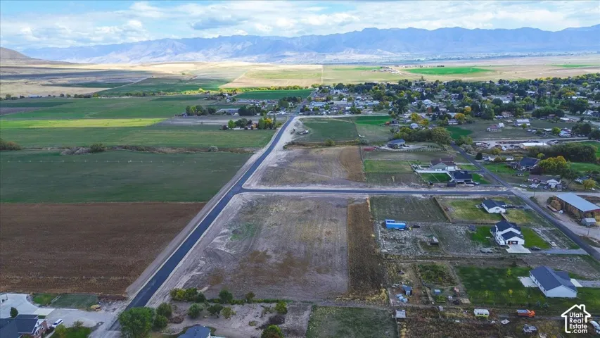 Aerial perspective of a vacant lot featuring paved street access and extensive mountain range scenery