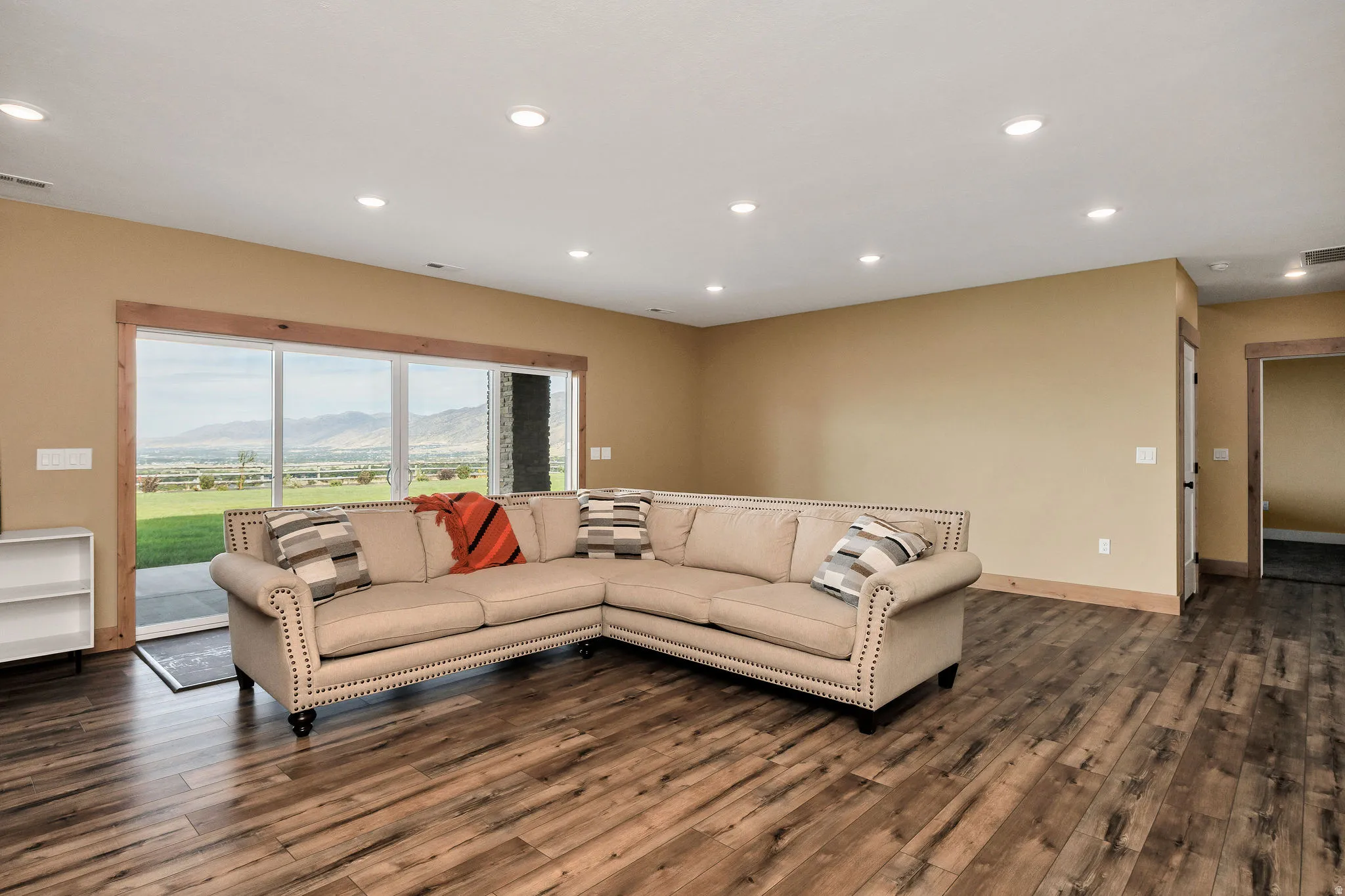 Expansive room featuring wood-finish flooring, recessed lighting, and a sliding glass door with wood trim