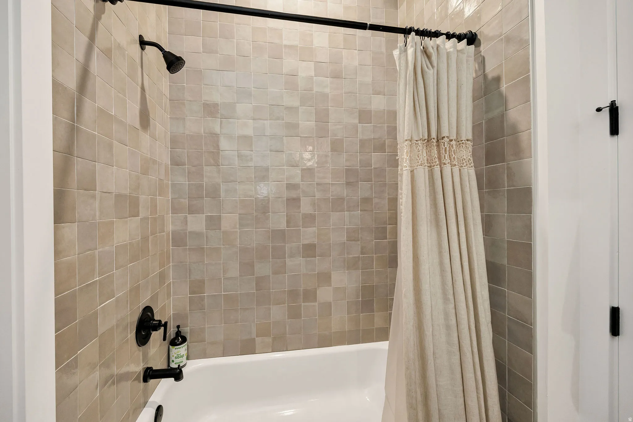 Bathtub with square tiled surround and matte black fixtures