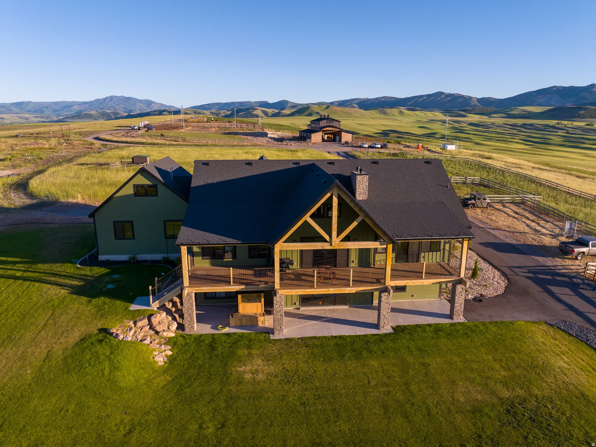 Expansive exterior featuring a large deck, lower patio, stone accents, and a paved driveway