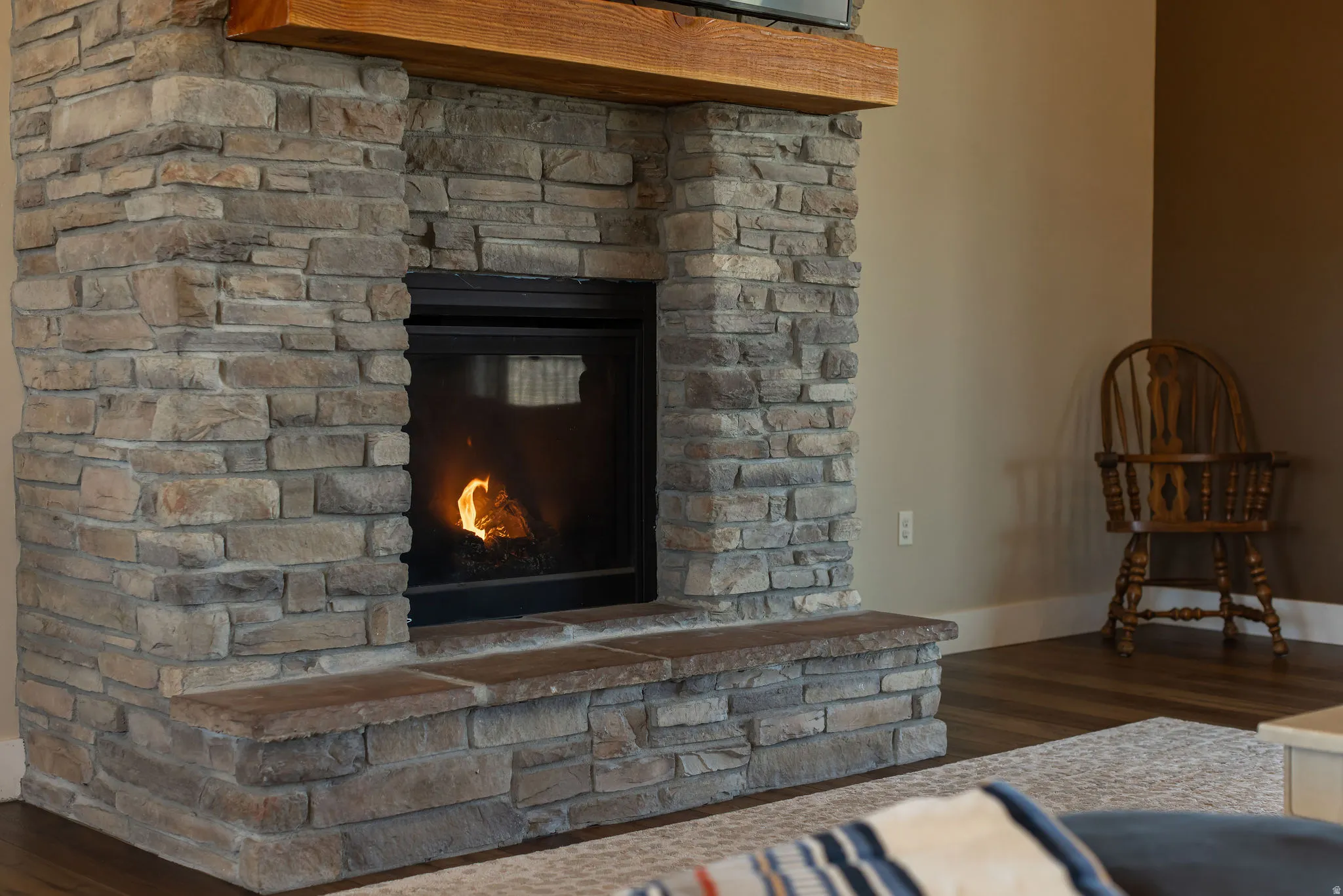 Stone-clad fireplace with a hearth and a substantial wood mantel