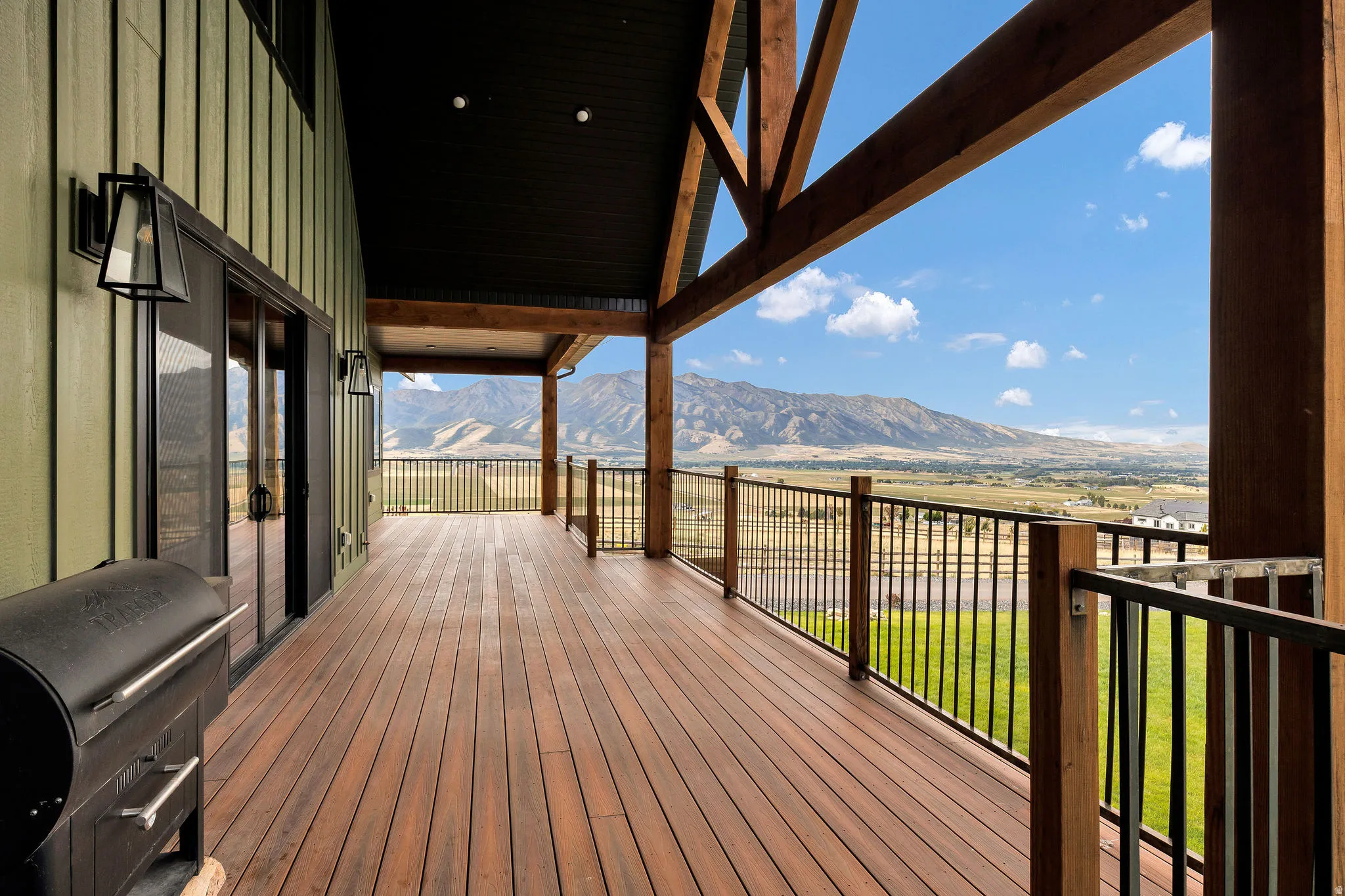 Expansive outdoor deck featuring wood flooring, exposed timber beams, and a black metal railing
