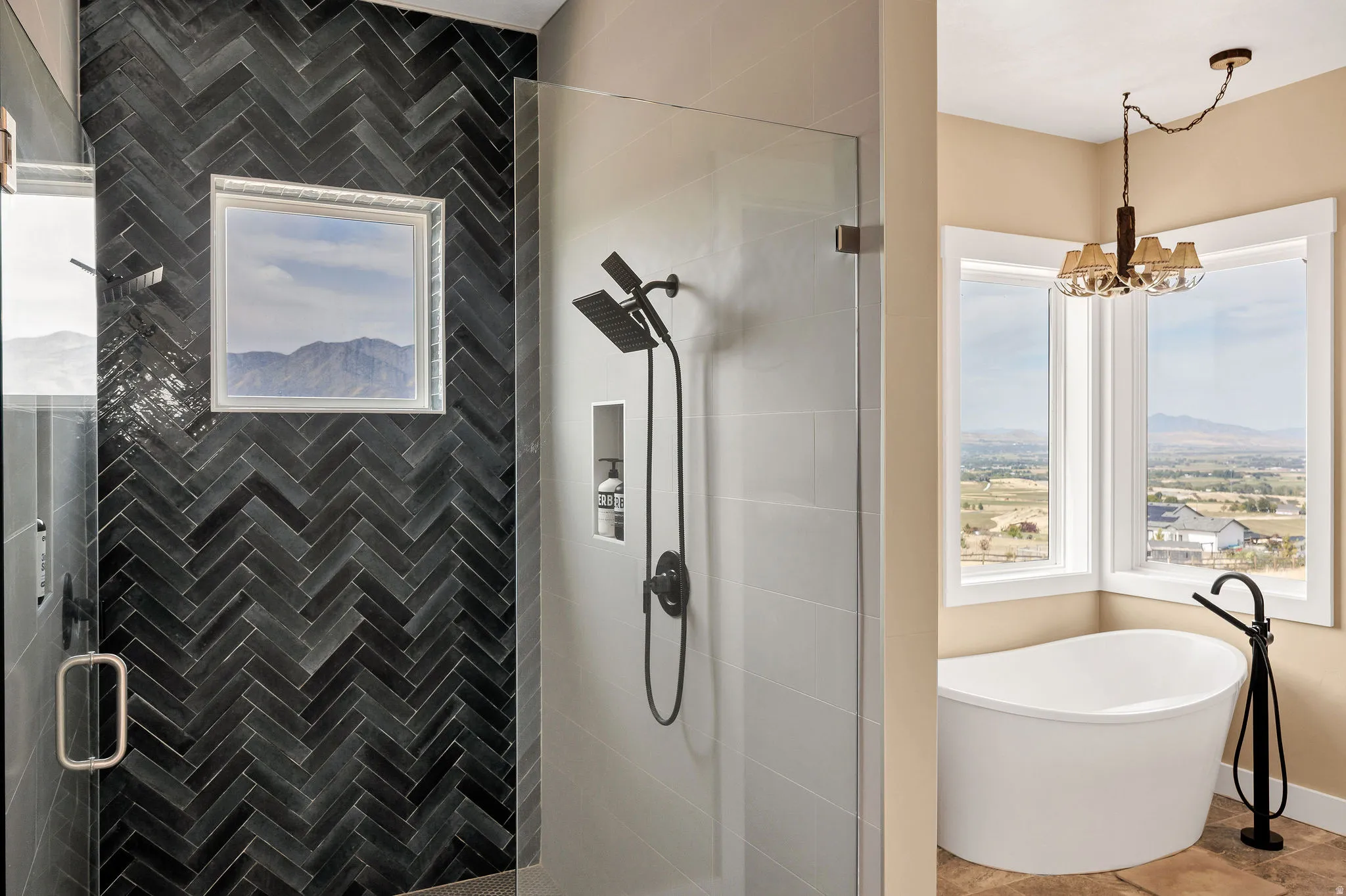 Glass-enclosed shower with black herringbone tile, dual shower heads, and built-in niche