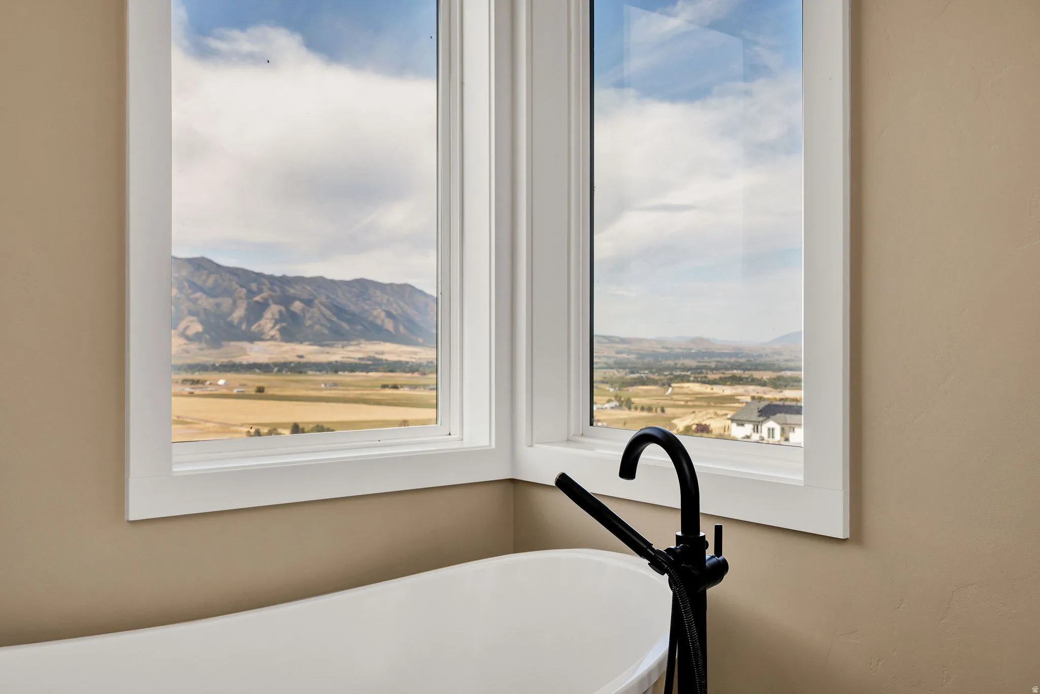 Freestanding soaking tub with floor-mounted matte black faucet, set against expansive mountain and valley scenery