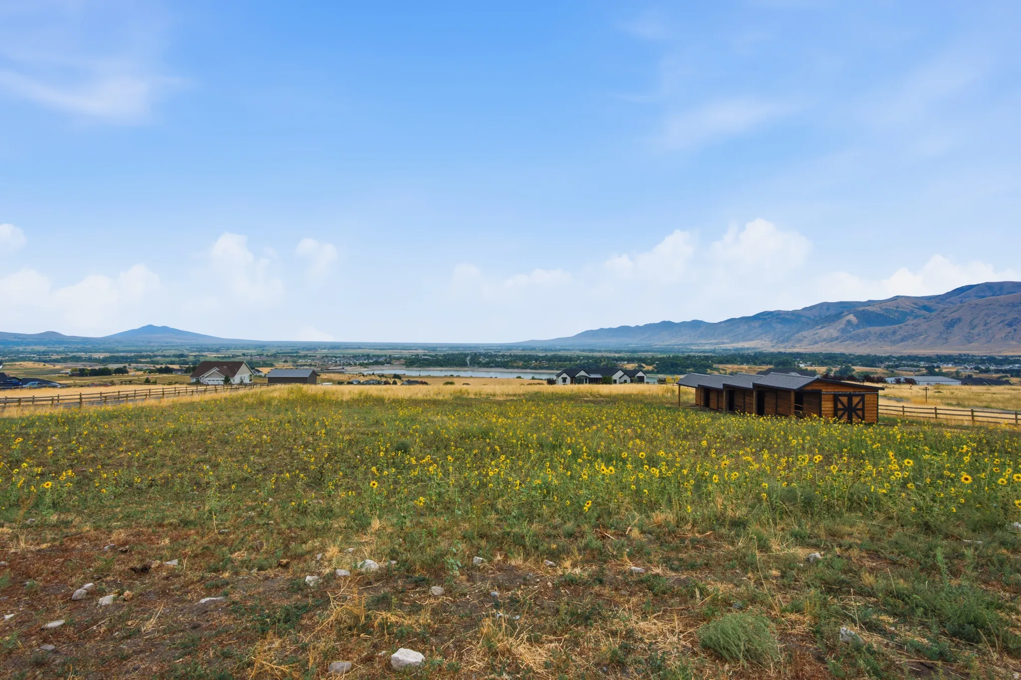 Expansive open landscape featuring a distant mountain range and multiple structures, including a white residence and several brown outbuildings