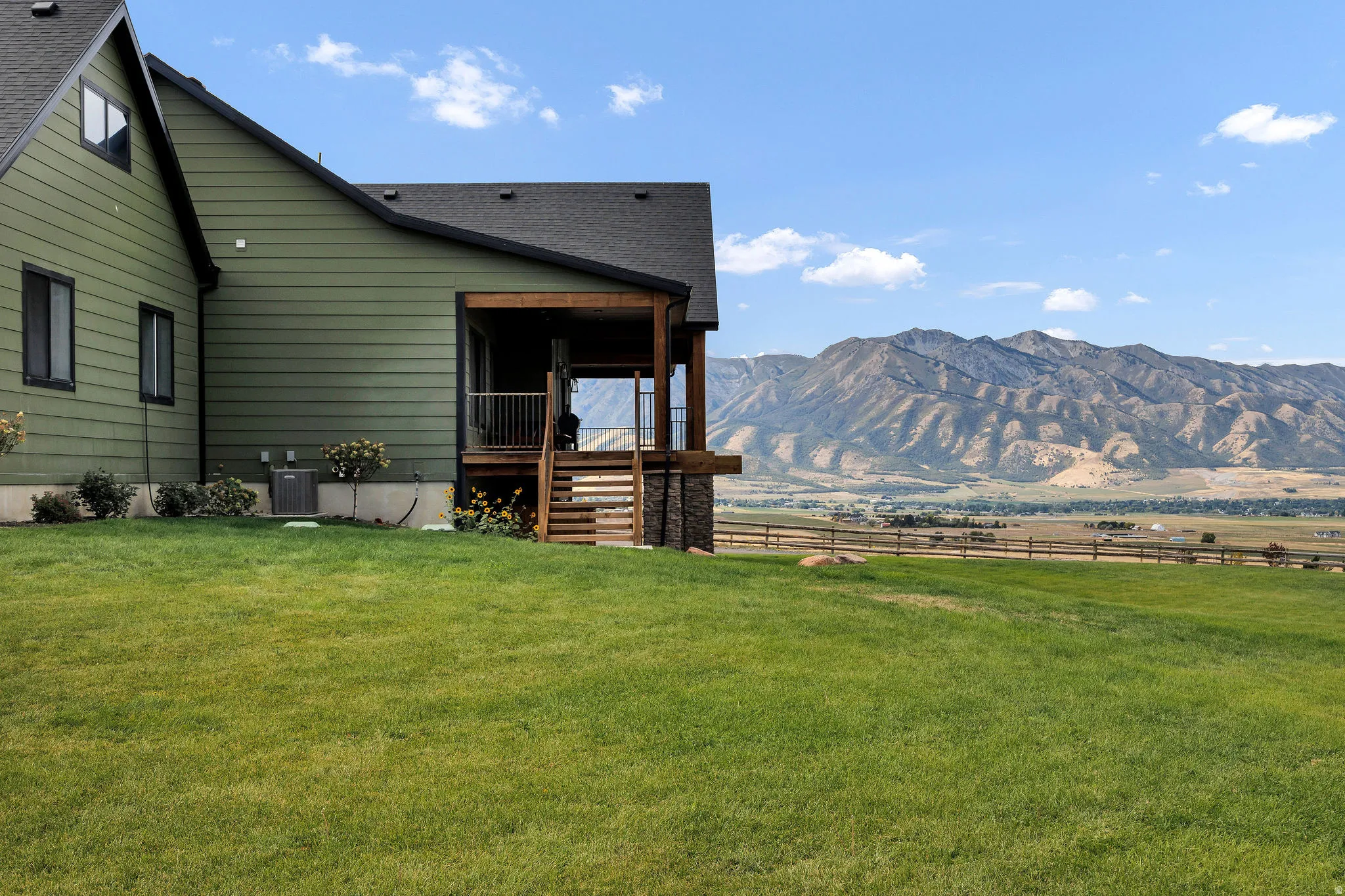 Green siding exterior with a covered wooden porch and stairs