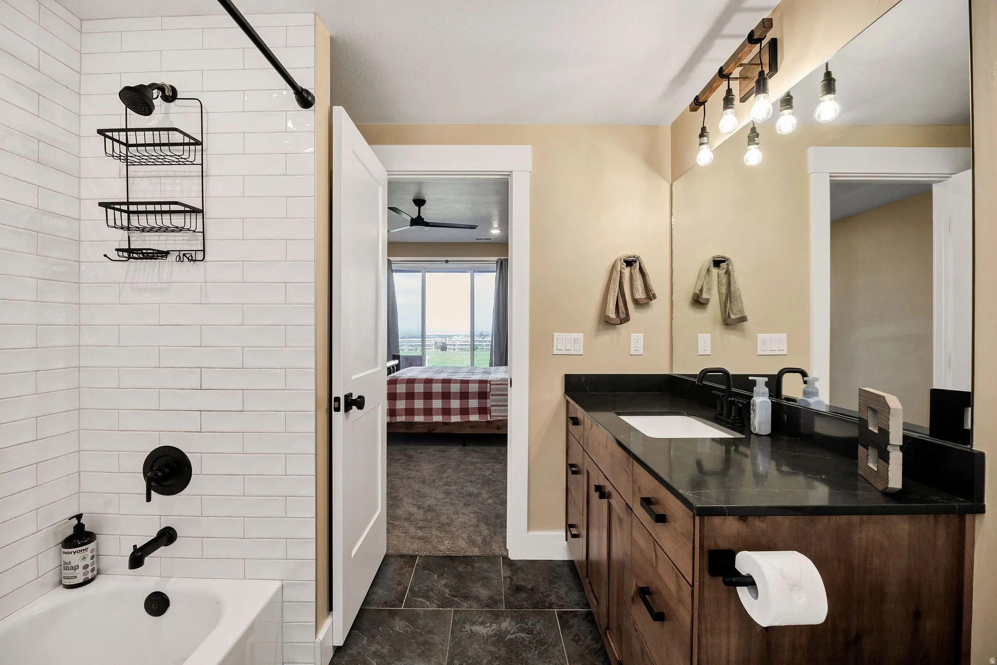Bathroom featuring a single vanity with a dark countertop, white undermount sink, and wood-finish cabinetry