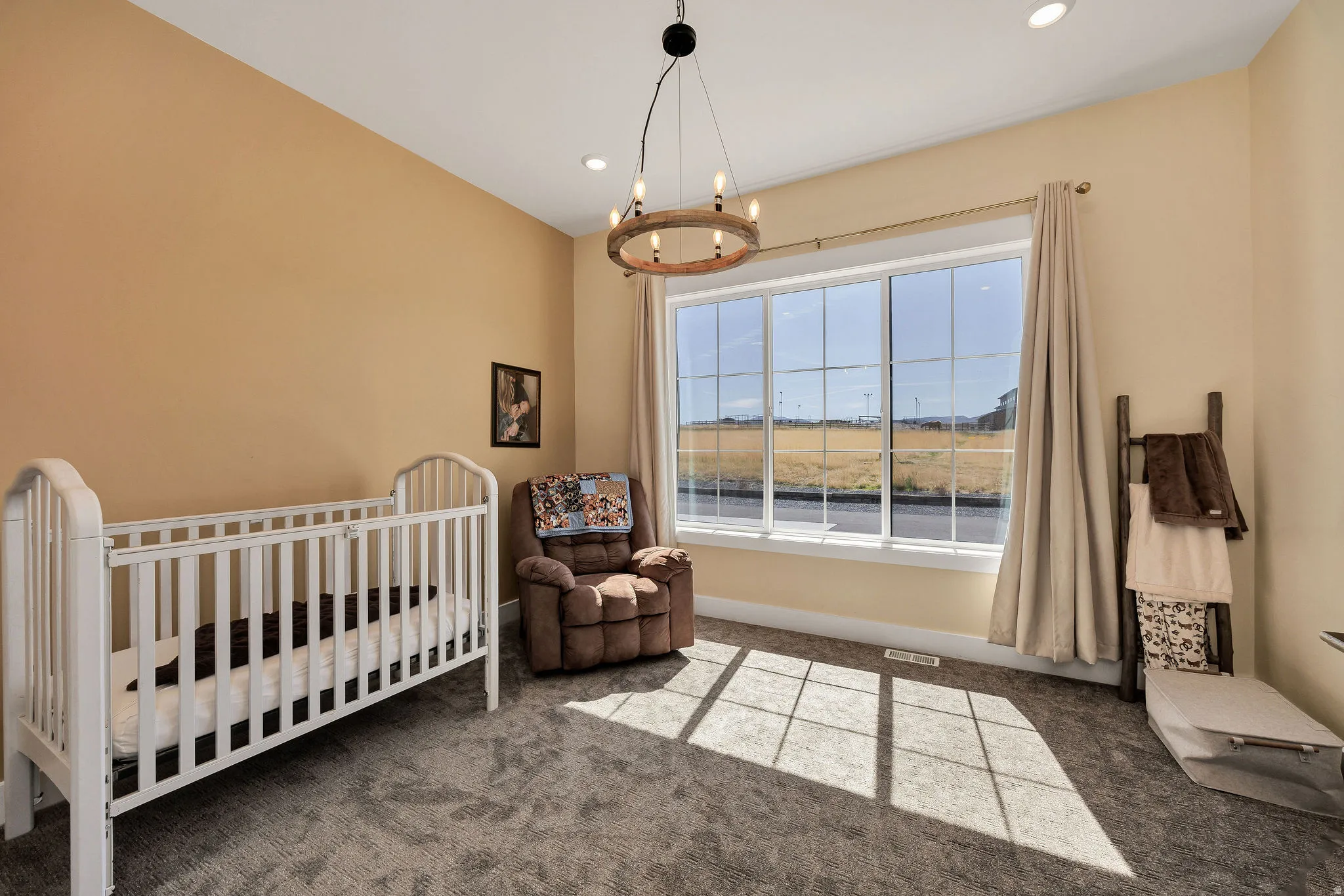 Recessed lighting, large multi-pane window, wood-finish chandelier, and neutral-toned walls