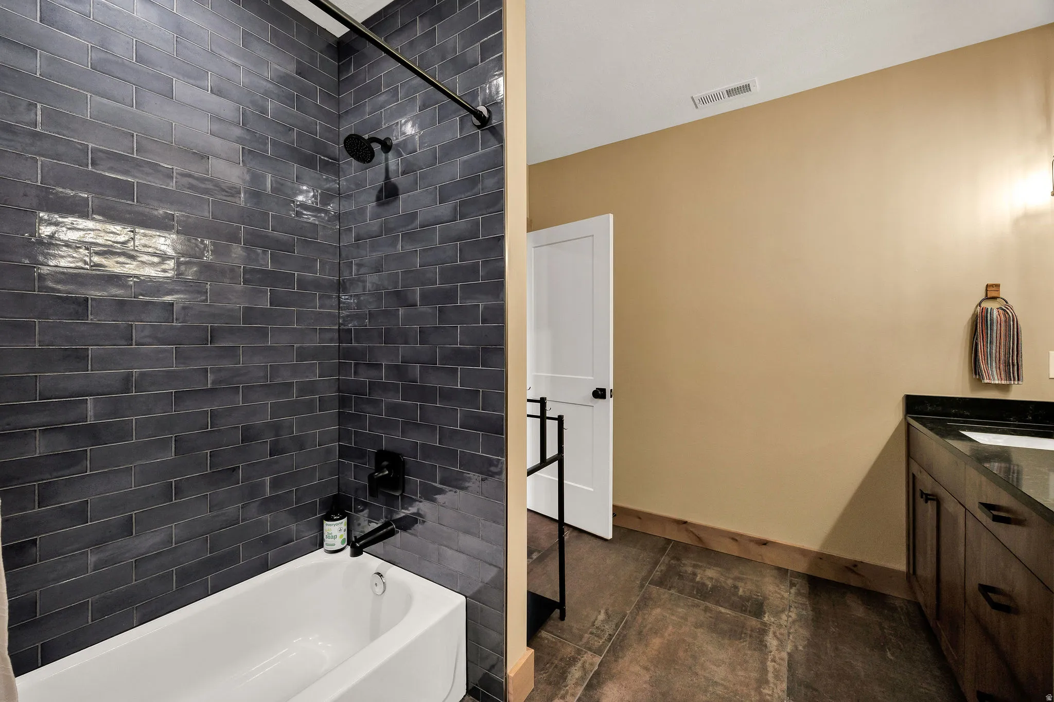 Bathtub with dark subway tile surround and matte black fixtures