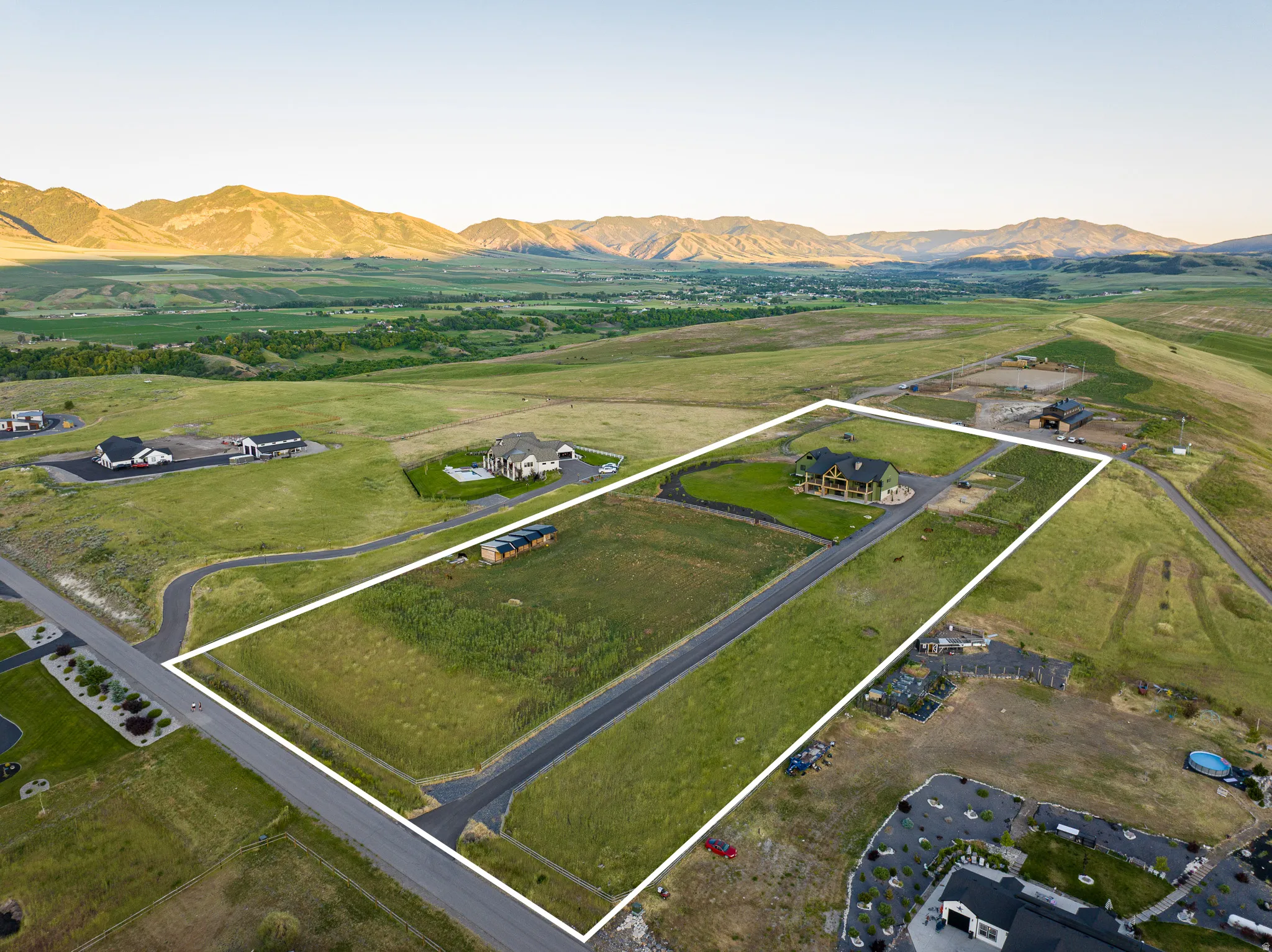 Spacious land parcel featuring a paved road, mountain backdrop, and expansive open terrain