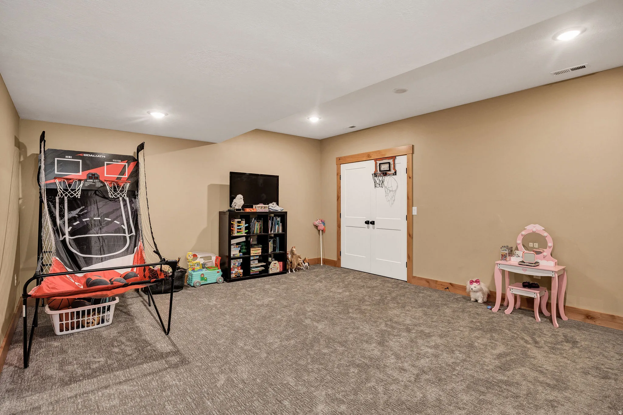 Recessed lighting illuminates a spacious room featuring wall-to-wall carpeting