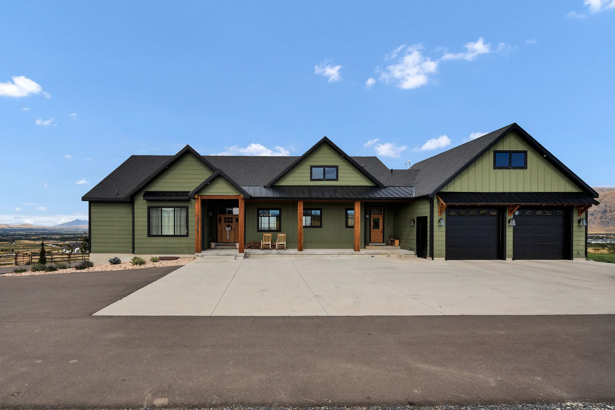 Contemporary green siding exterior with black trim, a gabled roofline, and a two-car garage with black doors