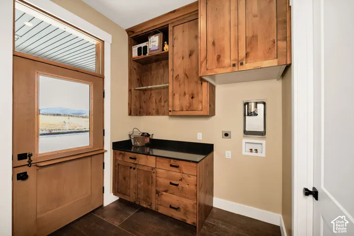 Wood-finish flooring, custom wood cabinetry, dark countertop, and a Dutch door with transom window