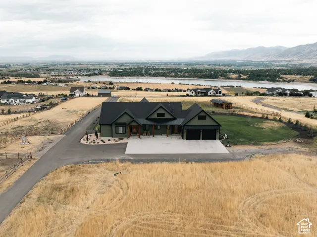 Modern farmhouse exterior with a multi-gabled roofline, attached two-car garage, expansive concrete driveway, and a paved private drive