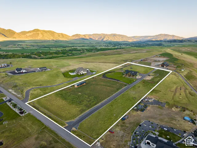 Spacious land parcel featuring a paved road, mountain backdrop, and expansive open terrain