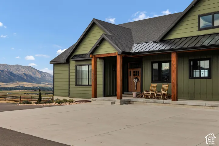 Green horizontal siding exterior with a black shingle roof, black metal roofing, and natural wood support columns