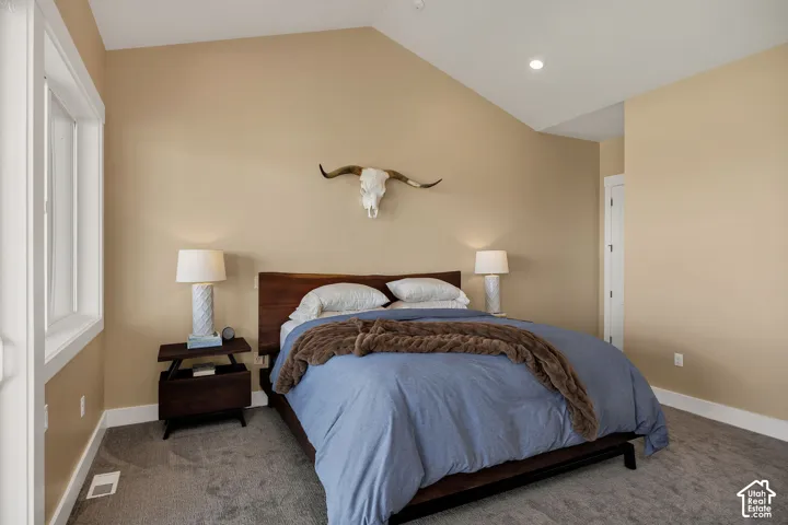 Vaulted ceiling, recessed lighting, white trim window, wood-finish bed frame, light-colored walls